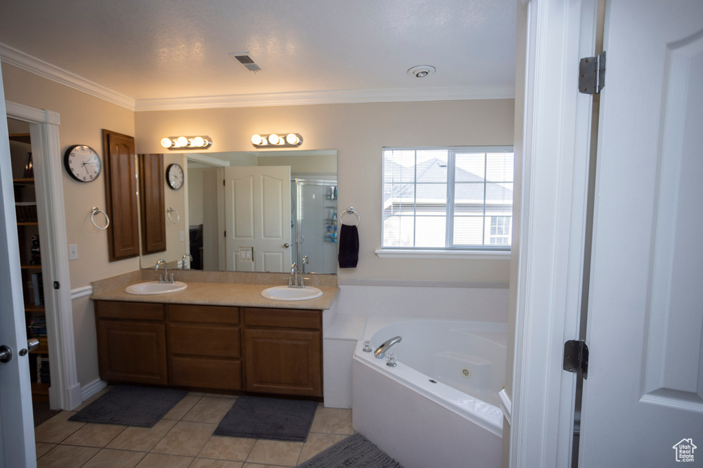Bathroom with vanity with extensive cabinet space, crown molding, a washtub, double sink, and tile flooring