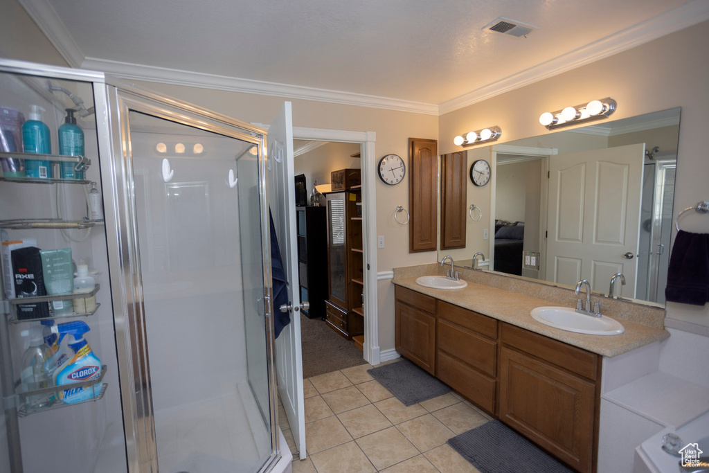 Bathroom featuring ornamental molding, an enclosed shower, double vanity, and tile floors
