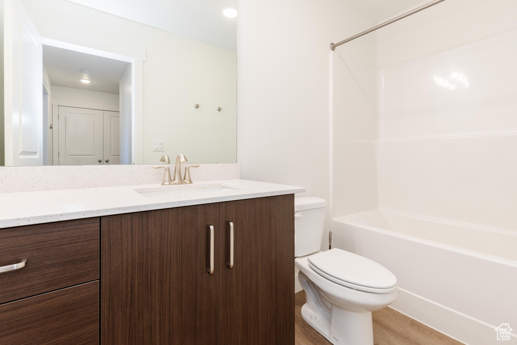 Full bathroom with shower / bath combination, hardwood / wood-style floors, vanity, and toilet
