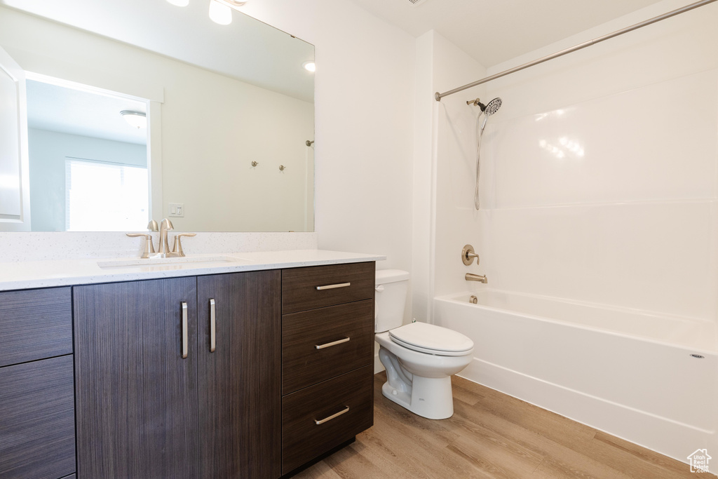 Full bathroom with bathtub / shower combination, hardwood / wood-style floors, vanity, and toilet