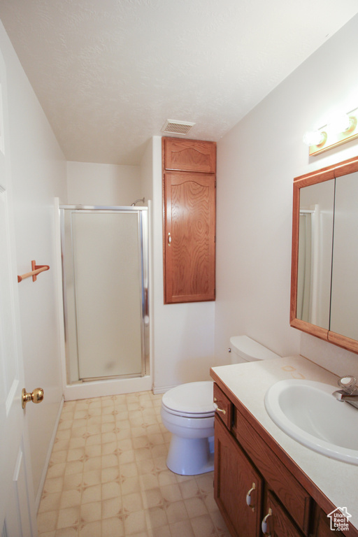 Bathroom with tile flooring, vanity, an enclosed shower, and toilet