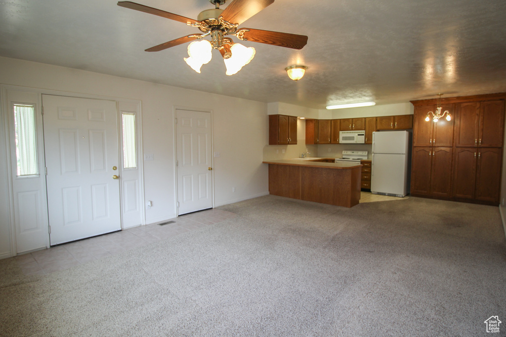 Kitchen with light carpet, decorative light fixtures, white appliances, and ceiling fan