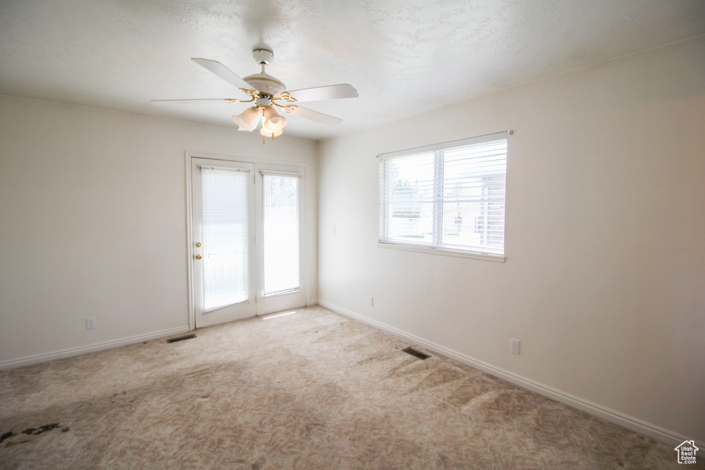 Spare room featuring light carpet and ceiling fan