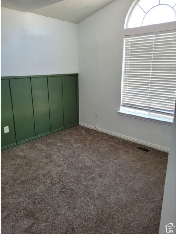Unfurnished bedroom featuring a closet, dark carpet, and multiple windows