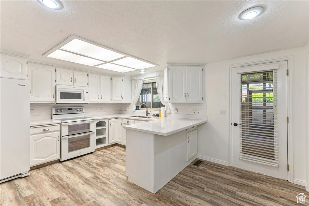 Kitchen with white cabinets, white appliances, and light wood-type flooring