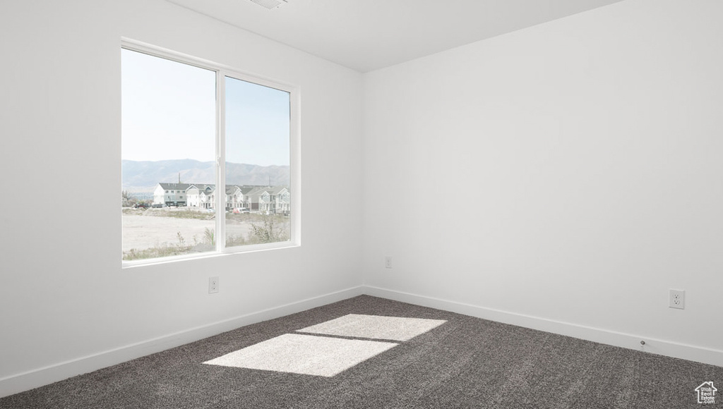 Unfurnished room with a mountain view and dark carpet