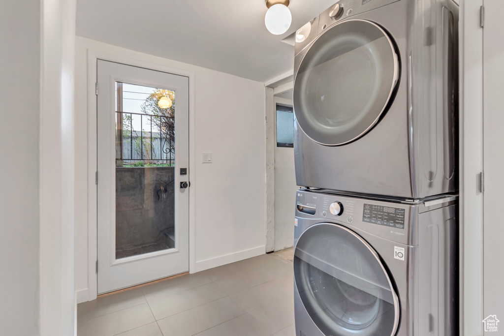 Laundry room featuring stacked washing maching and dryer and light tile floors