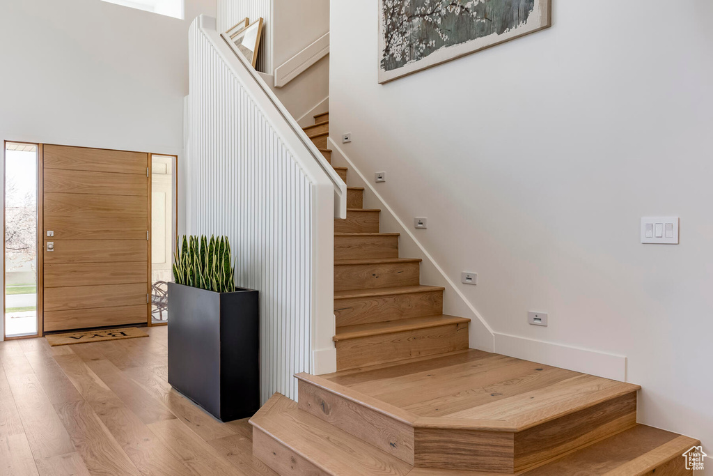 Staircase with light hardwood / wood-style flooring and a high ceiling