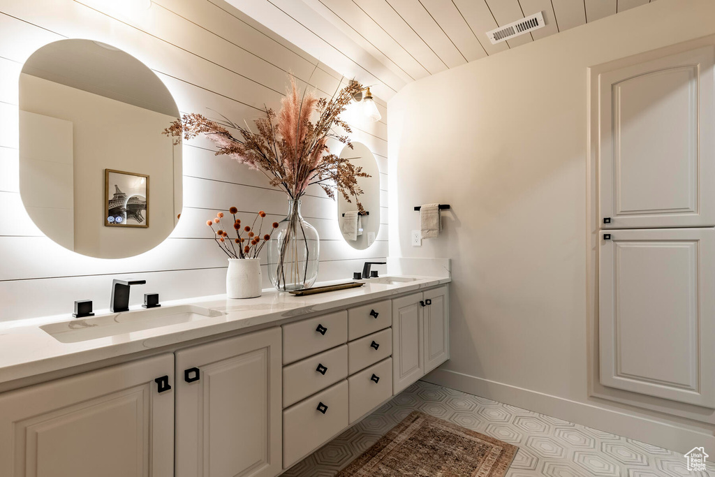Bathroom with dual bowl vanity, tile floors, and vaulted ceiling