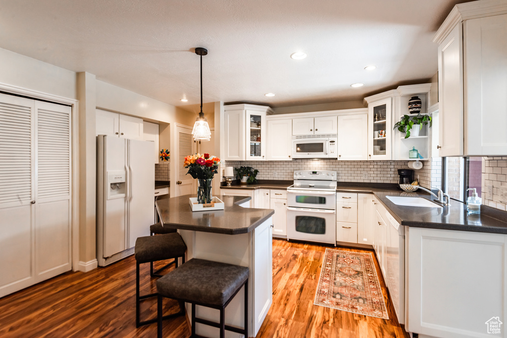 Kitchen featuring white cabinetry, tasteful backsplash, light hardwood / wood-style flooring, and white appliances