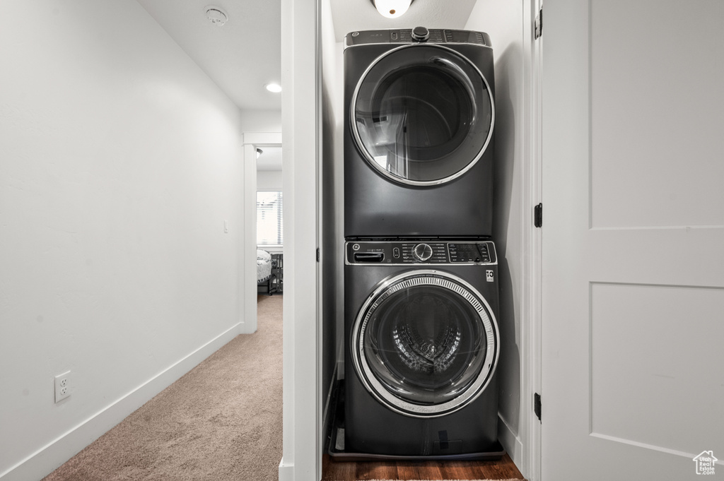 Laundry area featuring dark carpet and stacked washer and dryer