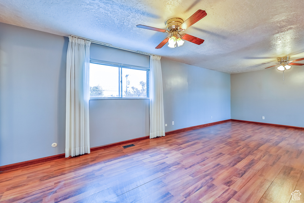 Spare room featuring ceiling fan, hardwood / wood-style flooring, and a textured ceiling