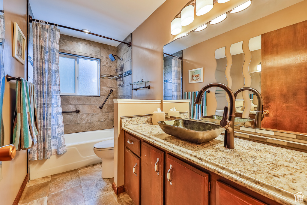 Full bathroom with tile flooring, oversized vanity, toilet, and shower / bath combo with shower curtain