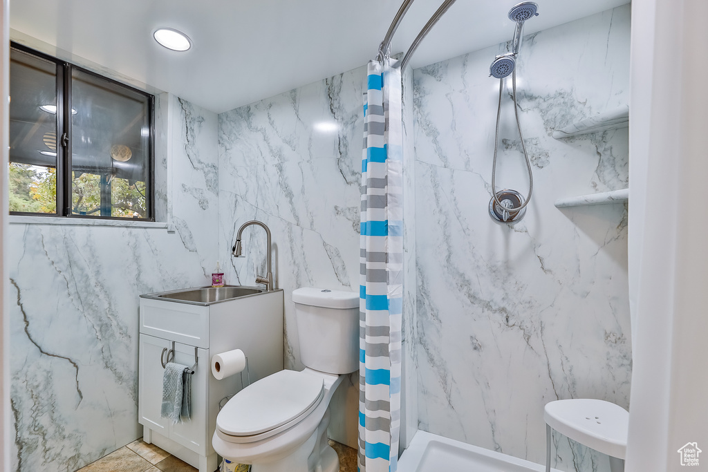 Bathroom featuring tile flooring, tile walls, a shower with curtain, sink, and toilet