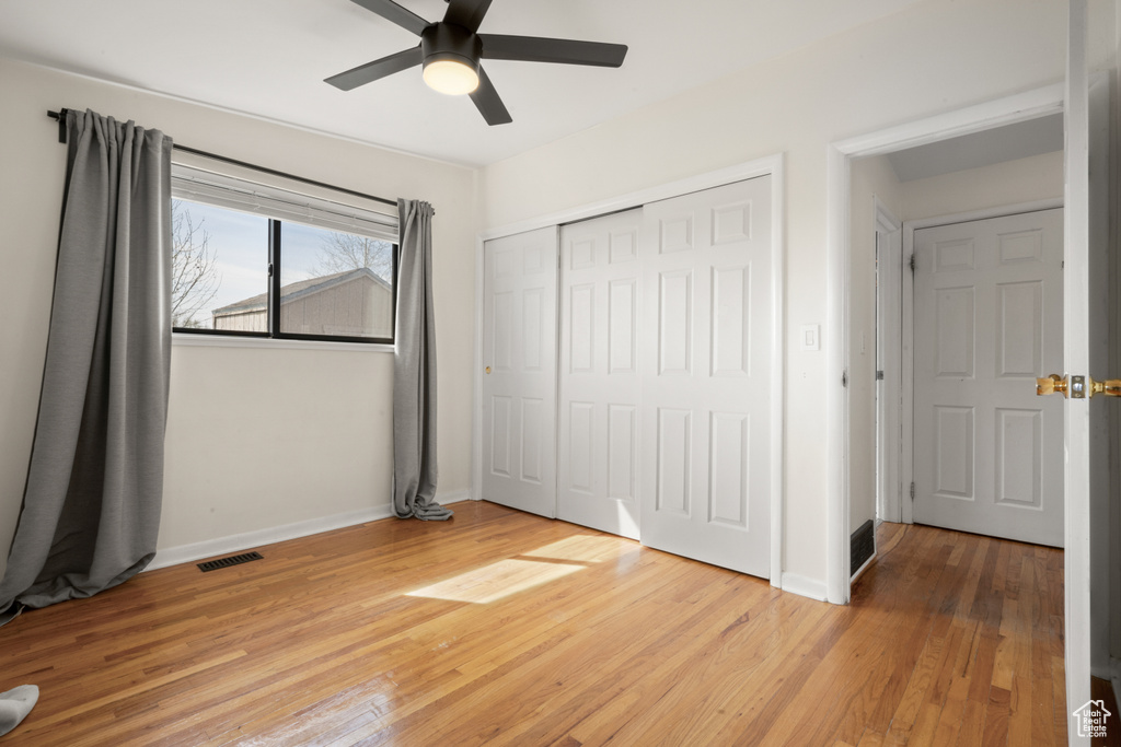 Unfurnished bedroom featuring a closet, light hardwood / wood-style floors, and ceiling fan