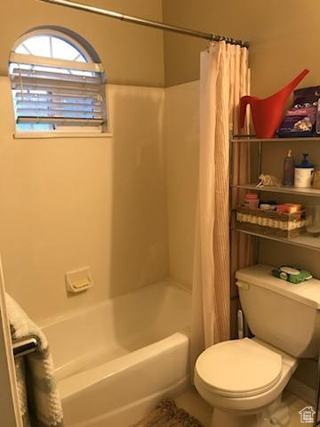 Bathroom featuring shower / tub combo, tile floors, and toilet