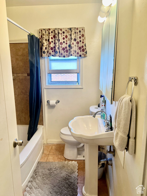Bathroom featuring shower / tub combo, toilet, and tile flooring