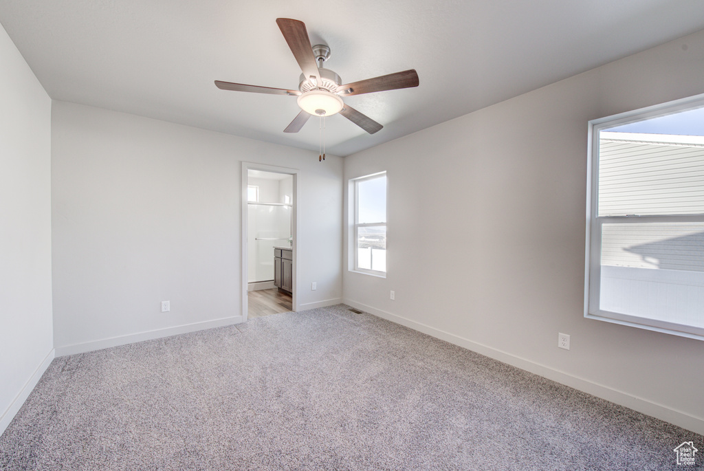 Unfurnished bedroom featuring light carpet, ceiling fan, and ensuite bathroom