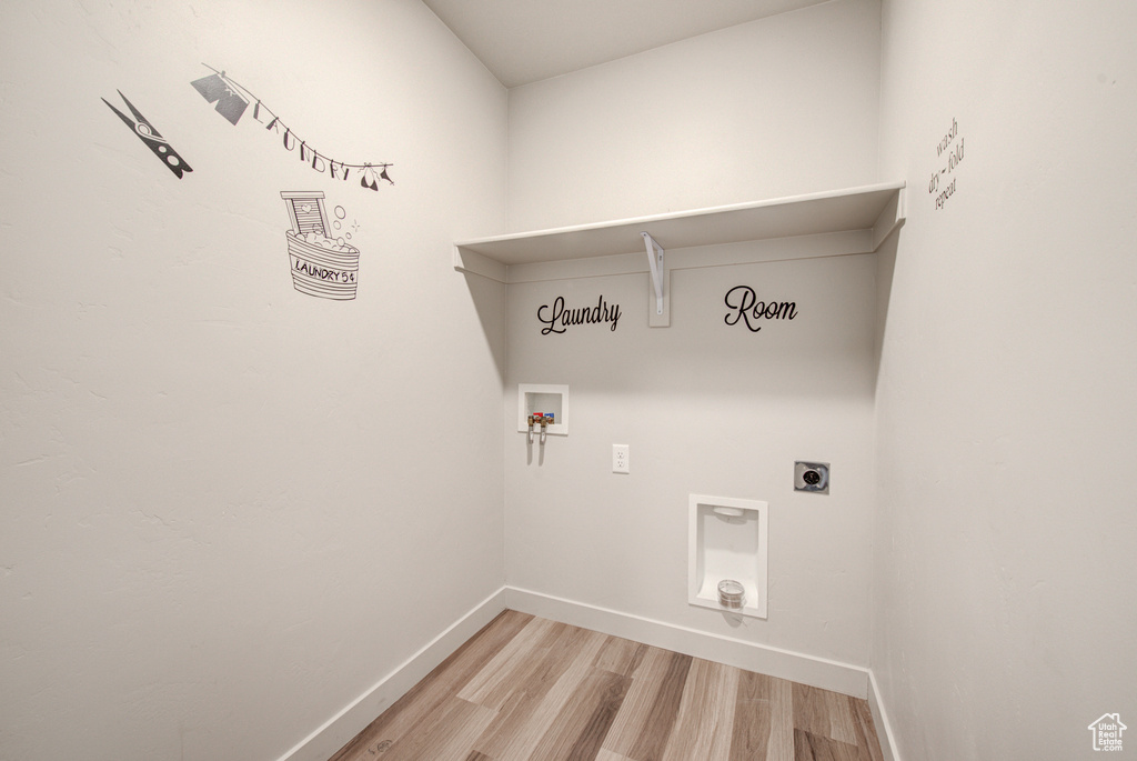 Washroom with hookup for an electric dryer, light hardwood / wood-style floors, and washer hookup