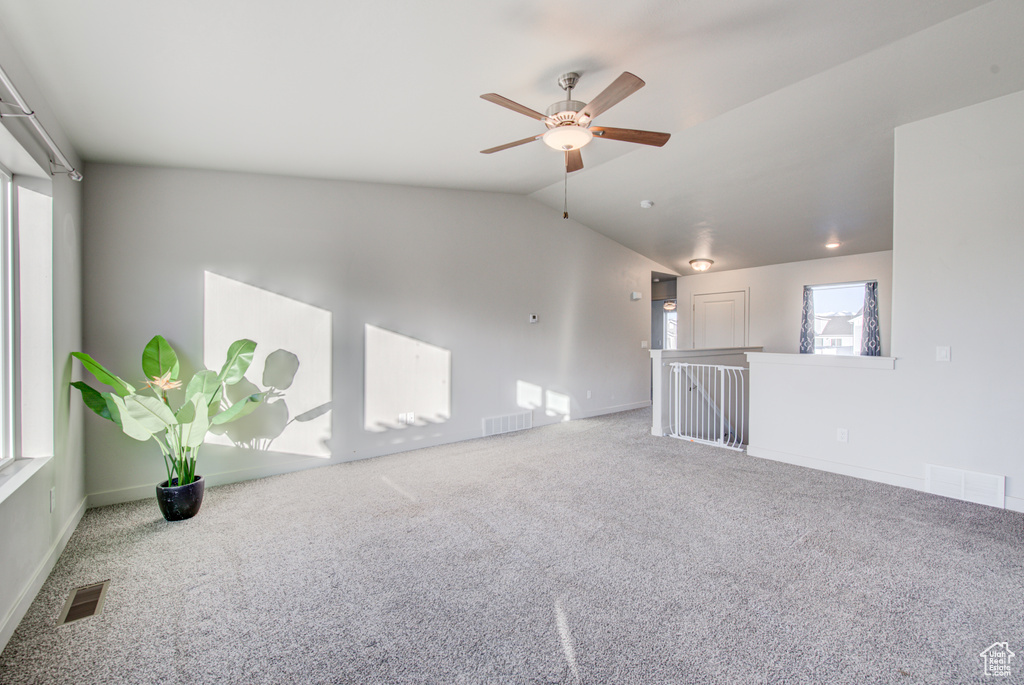 Carpeted spare room featuring ceiling fan and vaulted ceiling