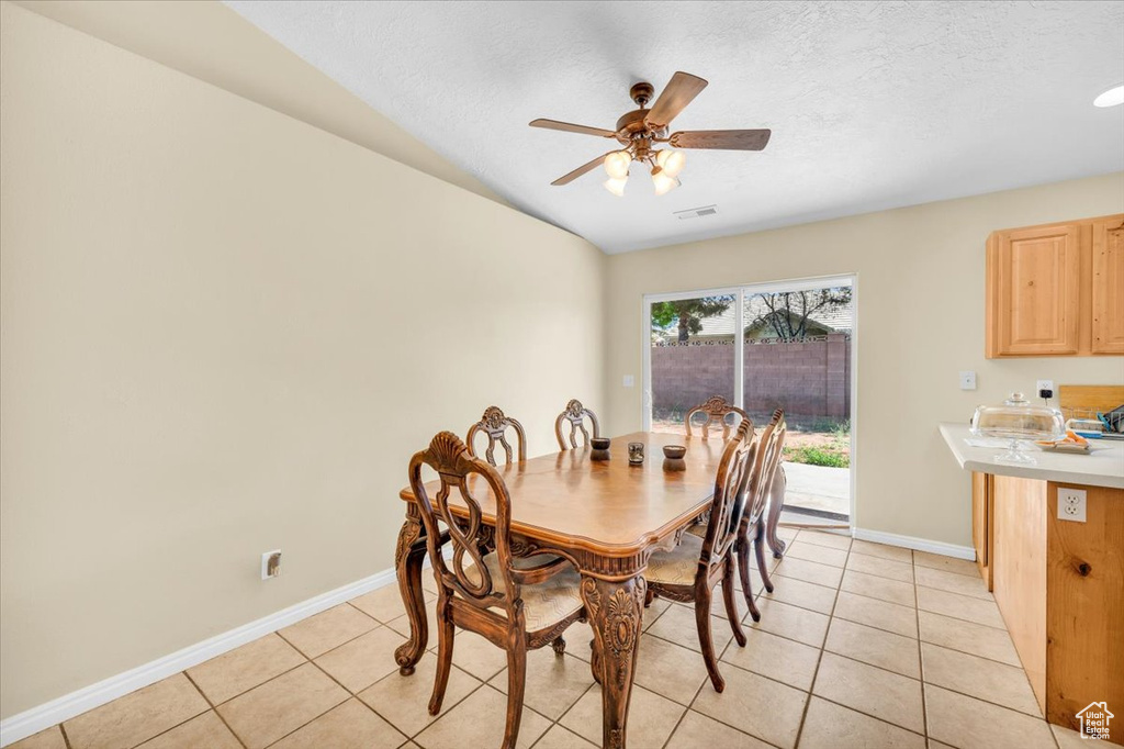 Dining room with ceiling fan, light tile flooring, and a textured ceiling