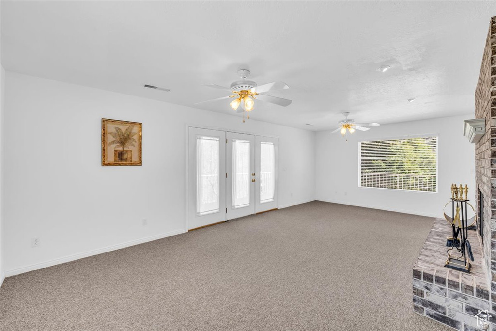 Unfurnished living room with ceiling fan, dark carpet, and a fireplace