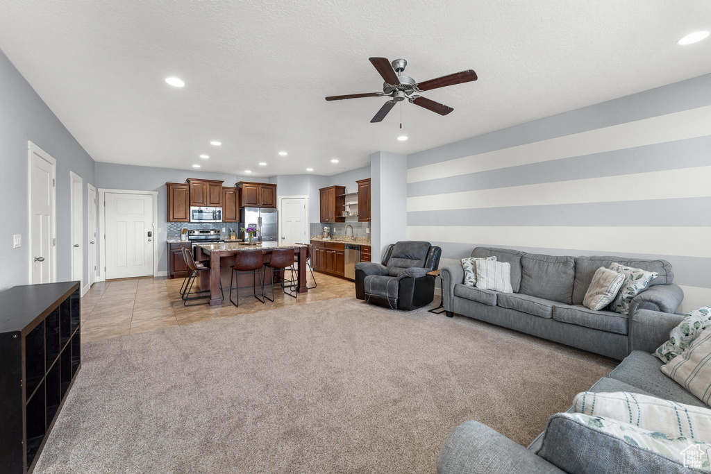 Carpeted living room with sink and ceiling fan