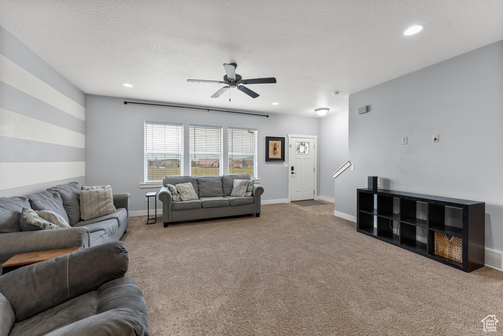 Living room featuring light carpet, ceiling fan, and a textured ceiling