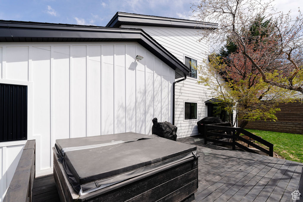 View of side of home featuring a hot tub and a wooden deck