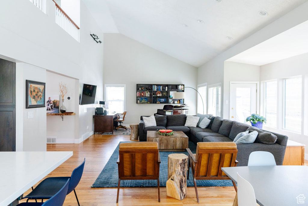Living room featuring plenty of natural light, high vaulted ceiling, and light hardwood / wood-style floors