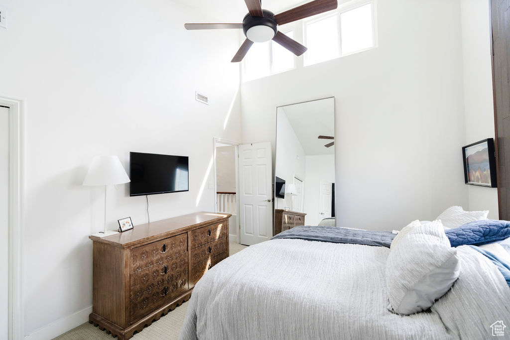 Carpeted bedroom featuring a high ceiling and ceiling fan