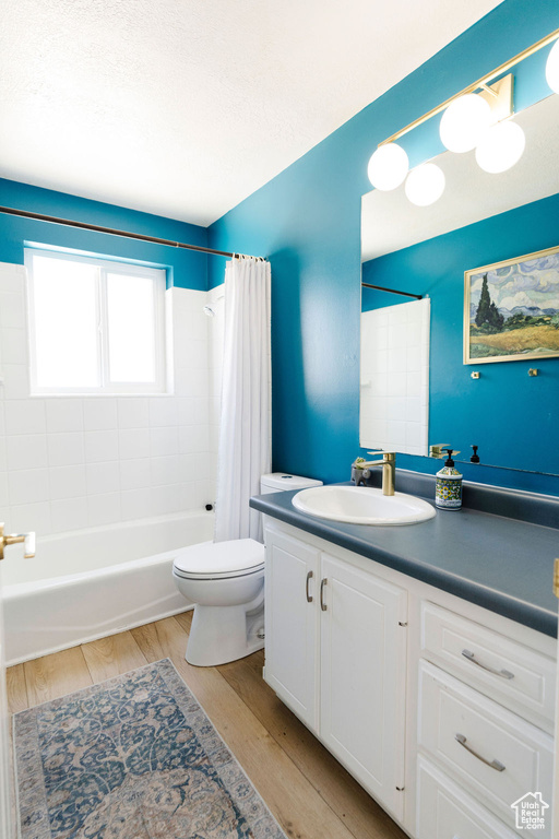 Full bathroom with wood-type flooring, shower / bath combo, vanity, and toilet