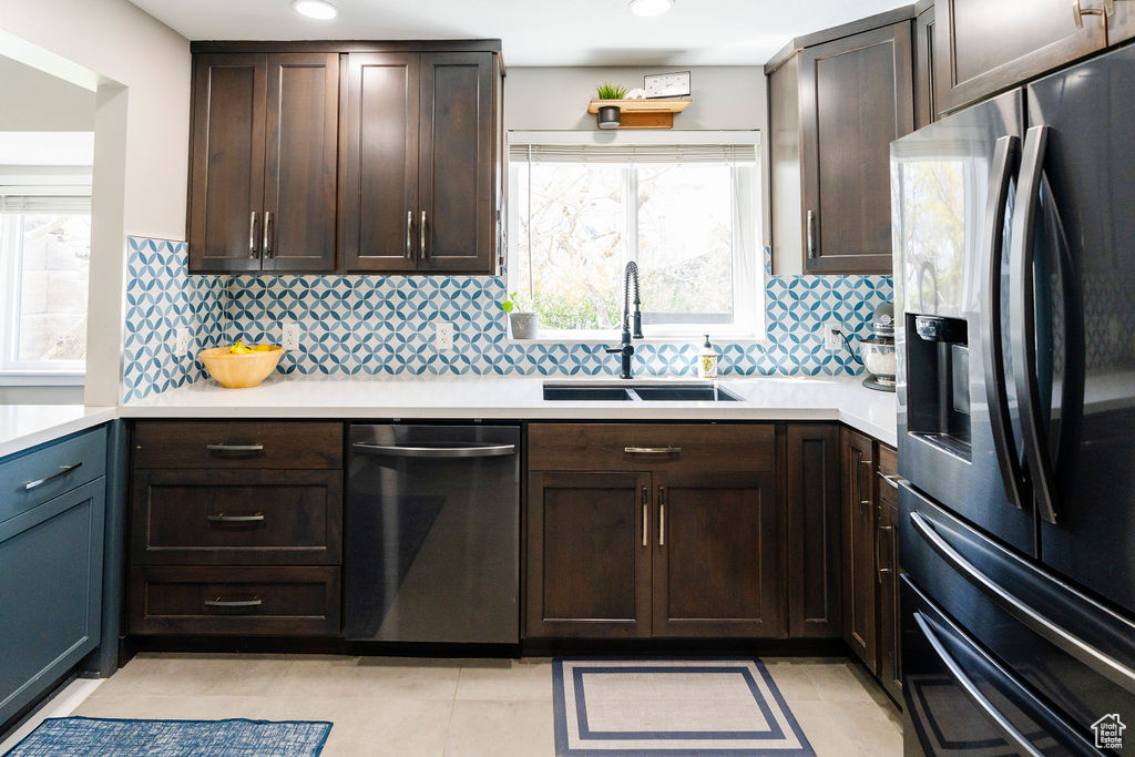 Kitchen featuring backsplash, sink, stainless steel appliances, and light tile floors