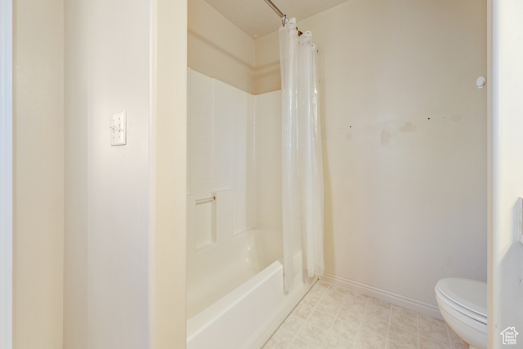 Bathroom featuring toilet, tile floors, and shower / tub combo with curtain