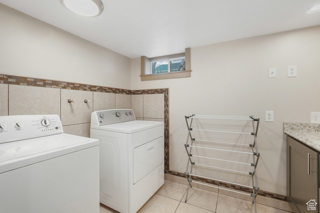Laundry area with tile walls, light tile flooring, and washer and clothes dryer