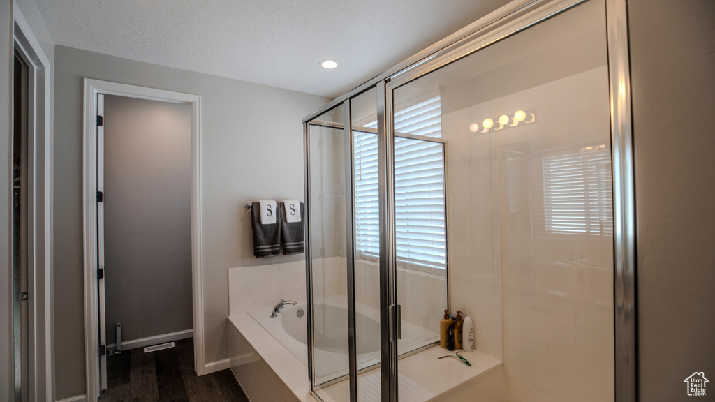 Bathroom with a healthy amount of sunlight, separate shower and tub, and hardwood / wood-style floors