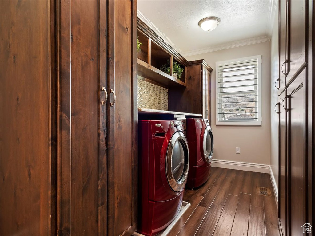 Laundry room with dark hardwood / wood-style floors, a textured ceiling, washer and dryer, and ornamental molding