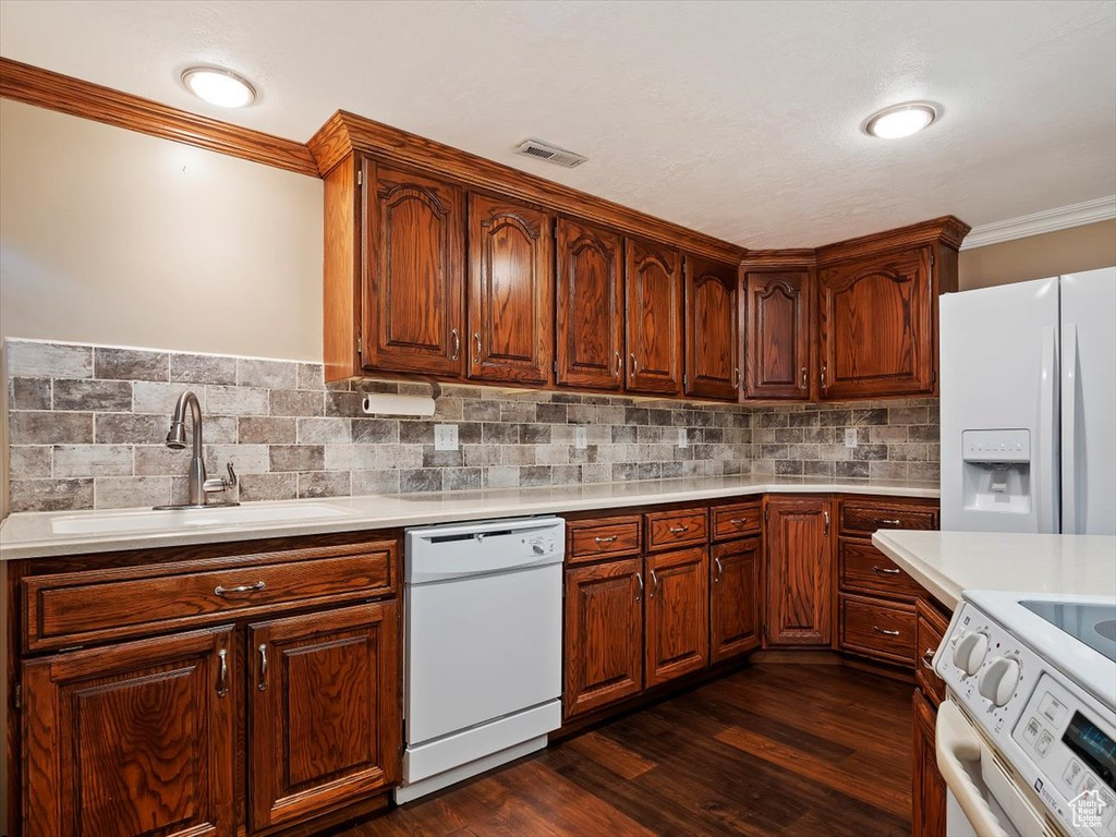 Kitchen with backsplash, white appliances, dark wood-type flooring, and sink