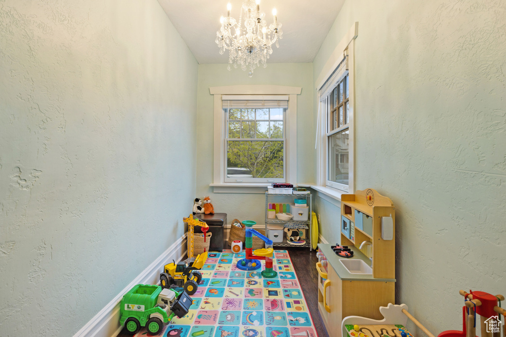 Playroom featuring dark wood-type flooring and a notable chandelier