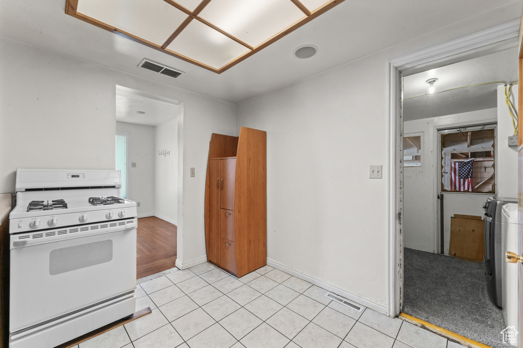 Kitchen featuring light colored carpet, white range with gas cooktop, and washer / clothes dryer