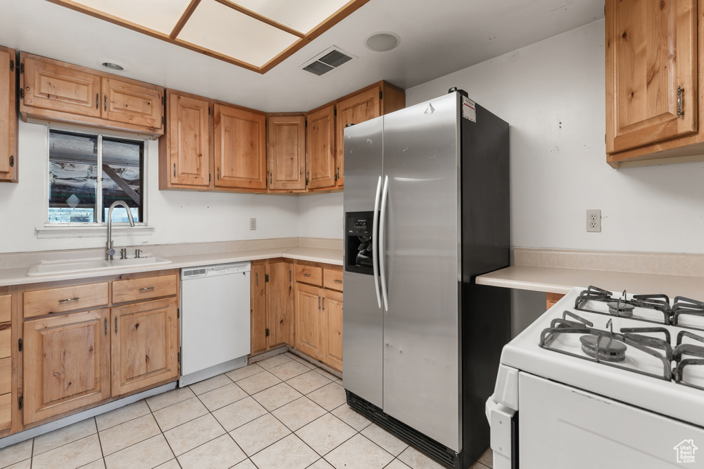 Kitchen featuring light tile floors, stainless steel fridge with ice dispenser, white dishwasher, and sink
