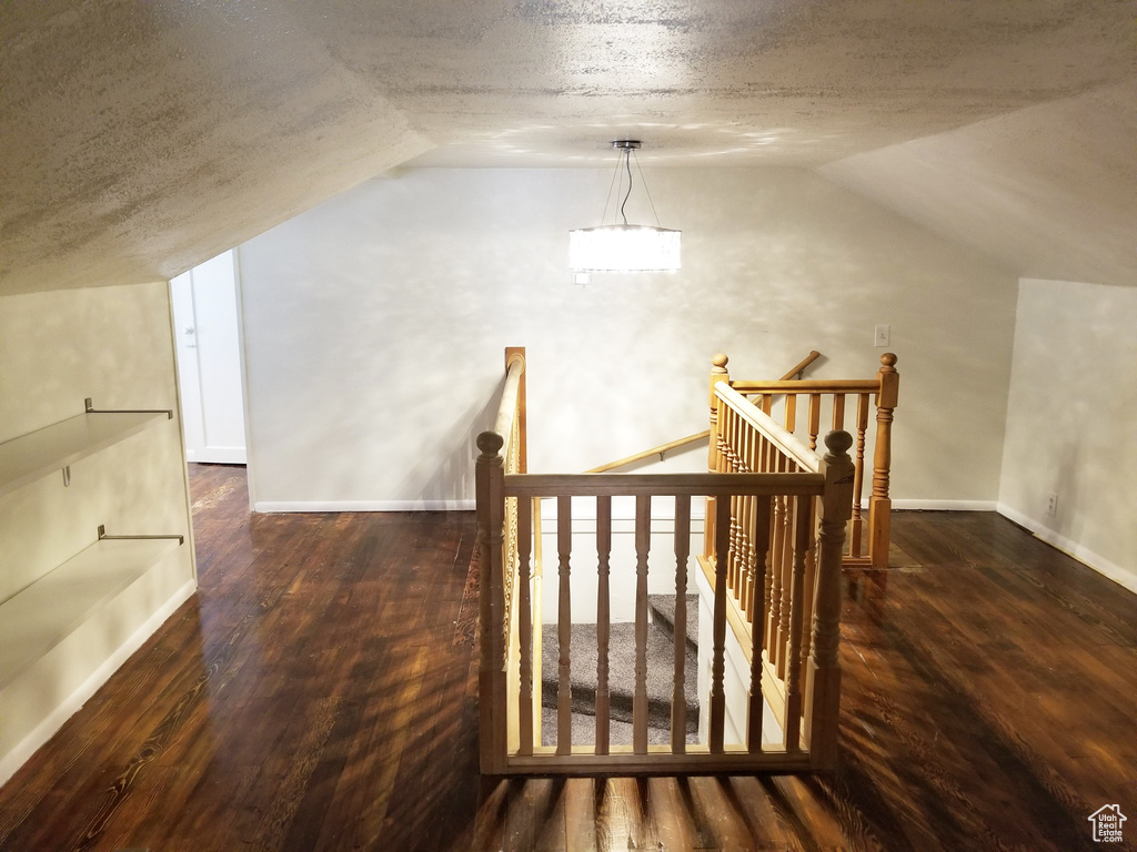 Bonus room with a textured ceiling, dark hardwood / wood-style flooring, and vaulted ceiling