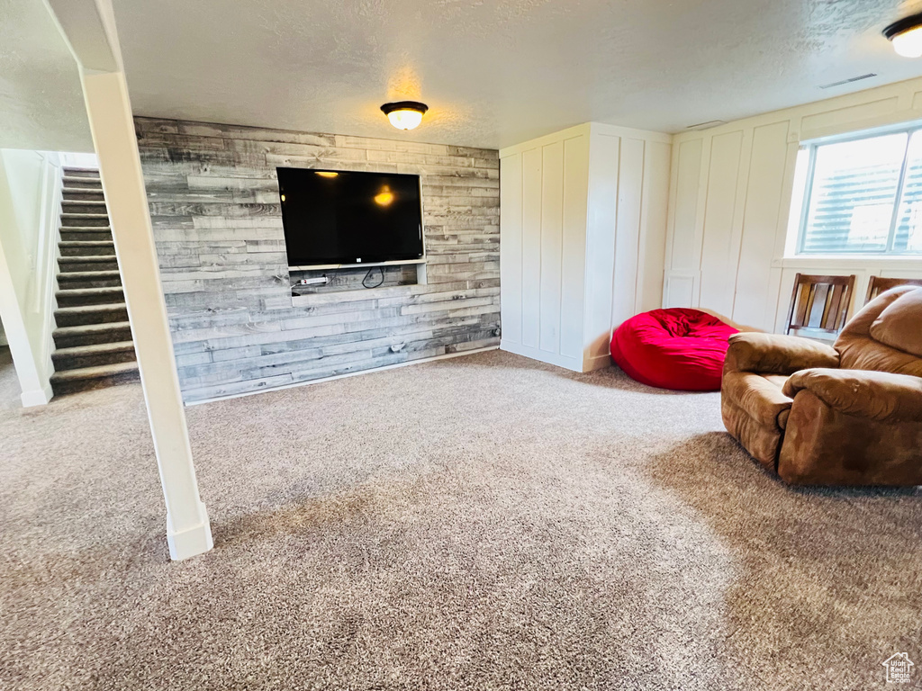 Sitting room with wood walls, light carpet, and a textured ceiling