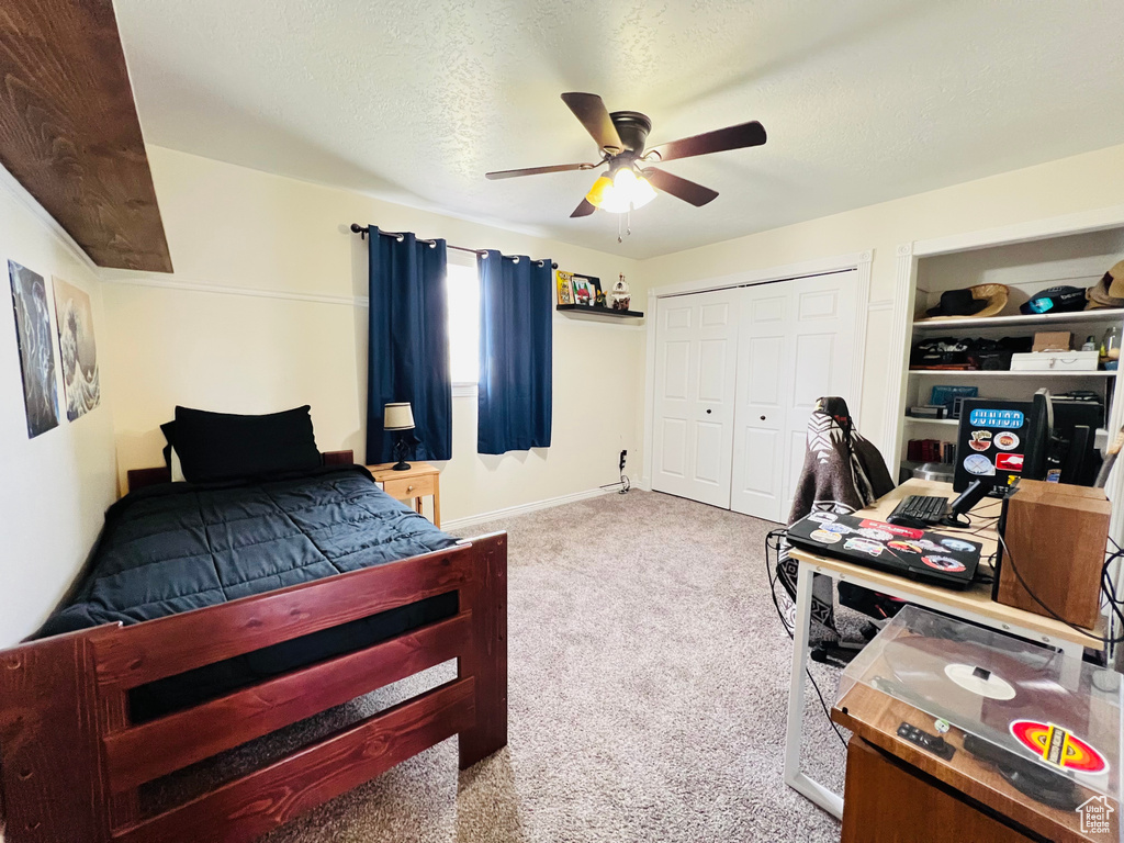 Bedroom featuring a closet, a textured ceiling, ceiling fan, and light carpet