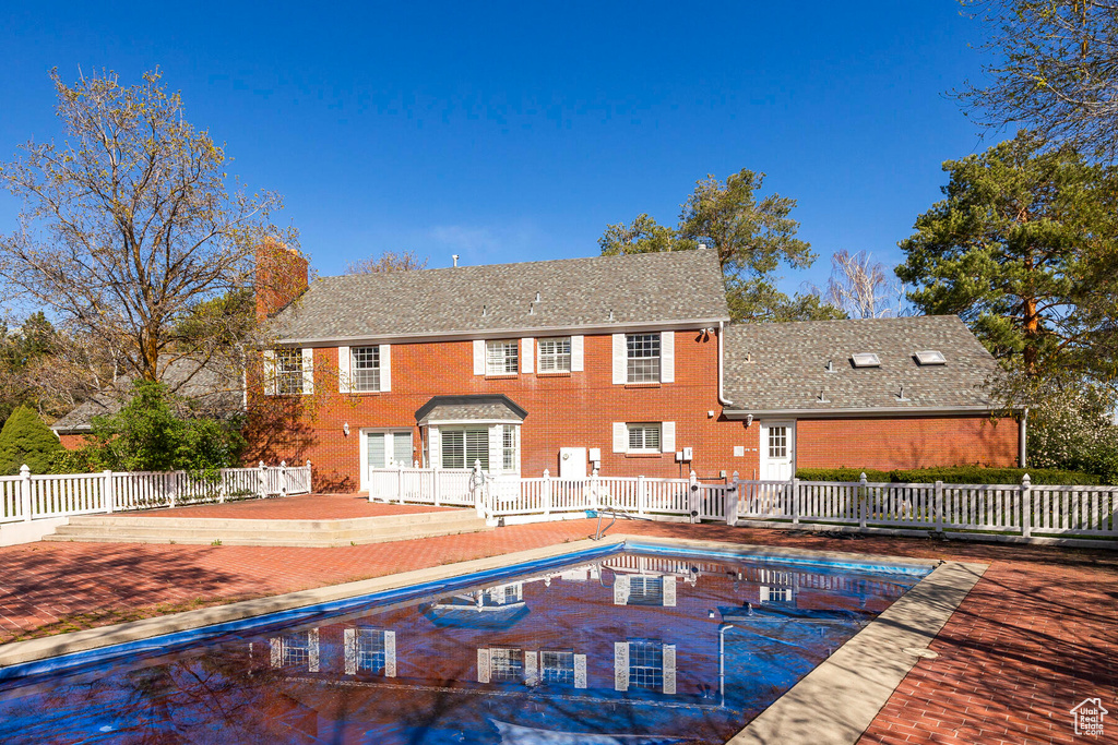 Rear view of property featuring a fenced in pool and a patio