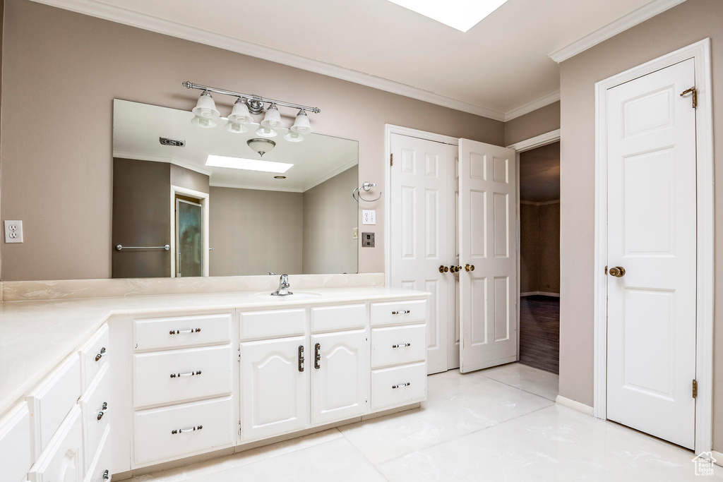 Bathroom featuring ornamental molding, tile floors, and vanity