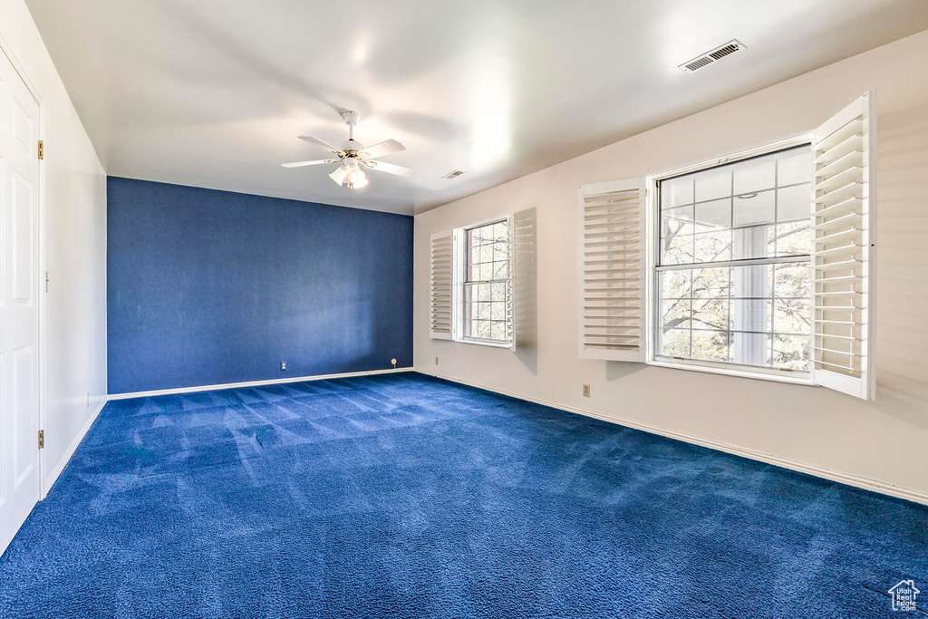Spare room featuring ceiling fan and dark carpet
