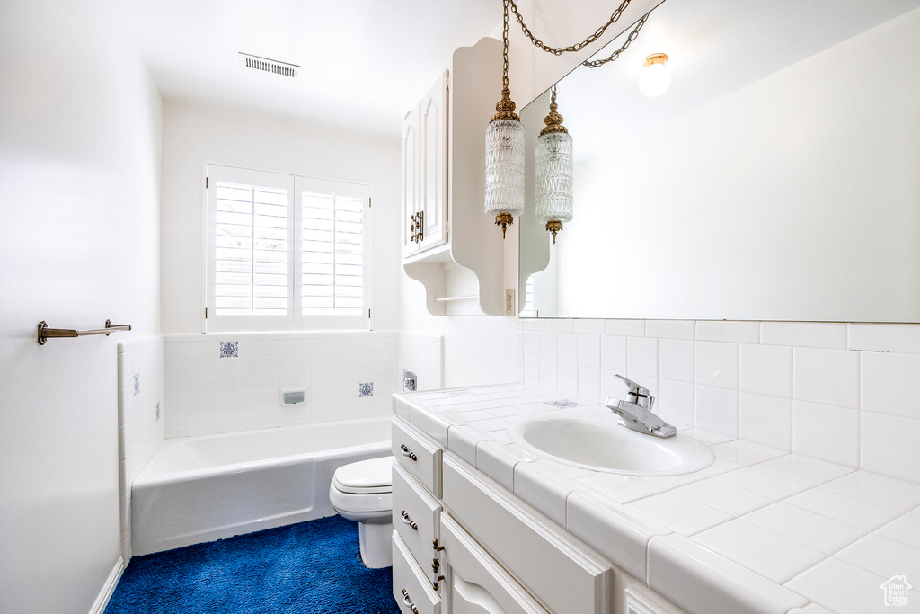 Bathroom featuring a washtub, vanity, backsplash, and toilet