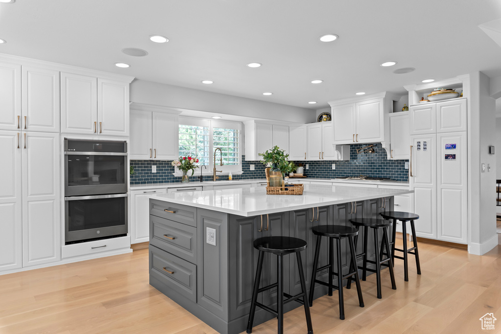 Kitchen with a center island, light hardwood / wood-style flooring, a breakfast bar, and white cabinetry