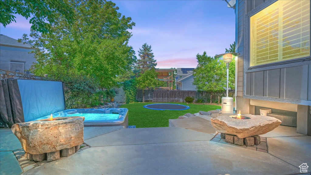 Patio terrace at dusk featuring a pool and a yard